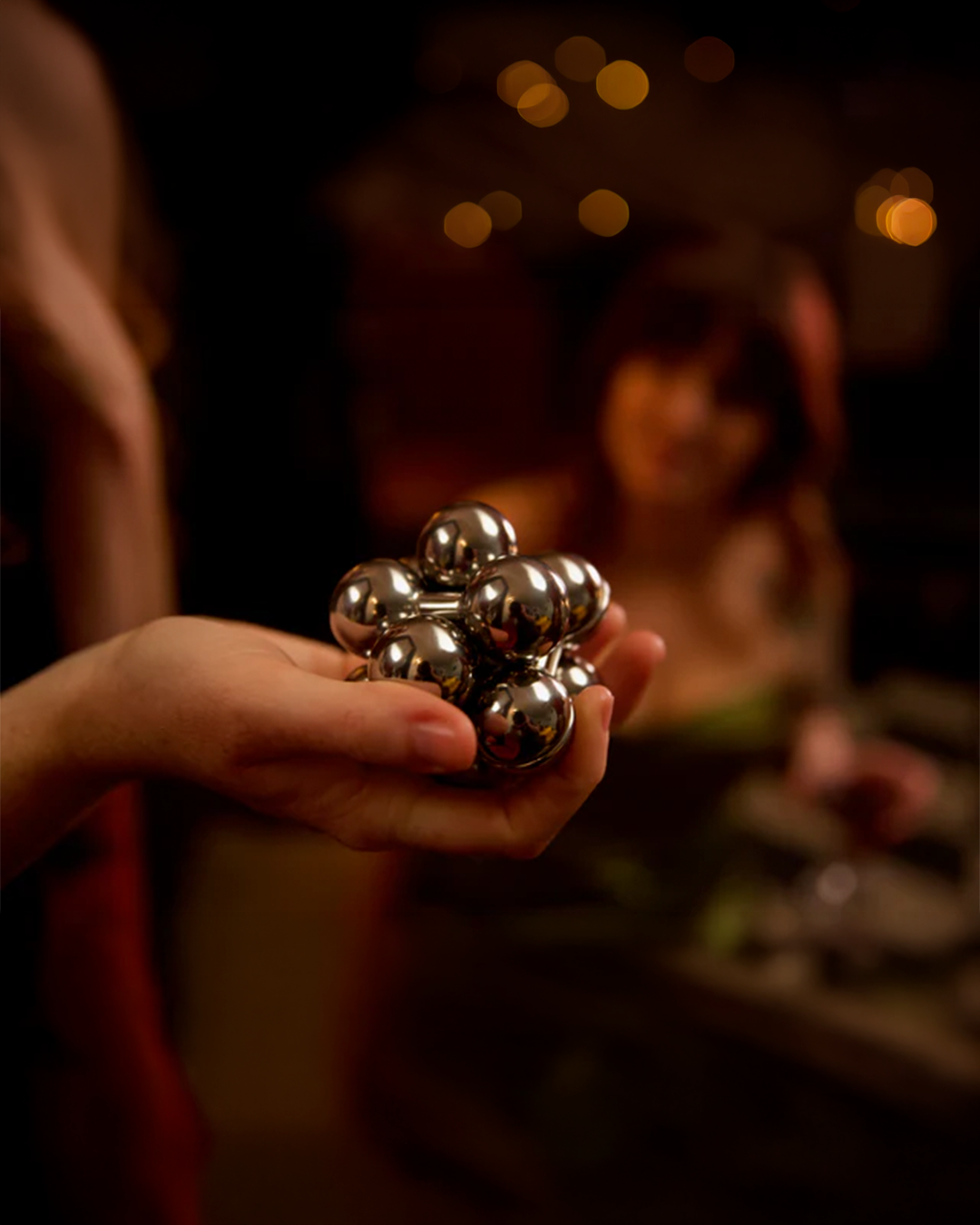 Person holding a metallic fidget cube with blurred background