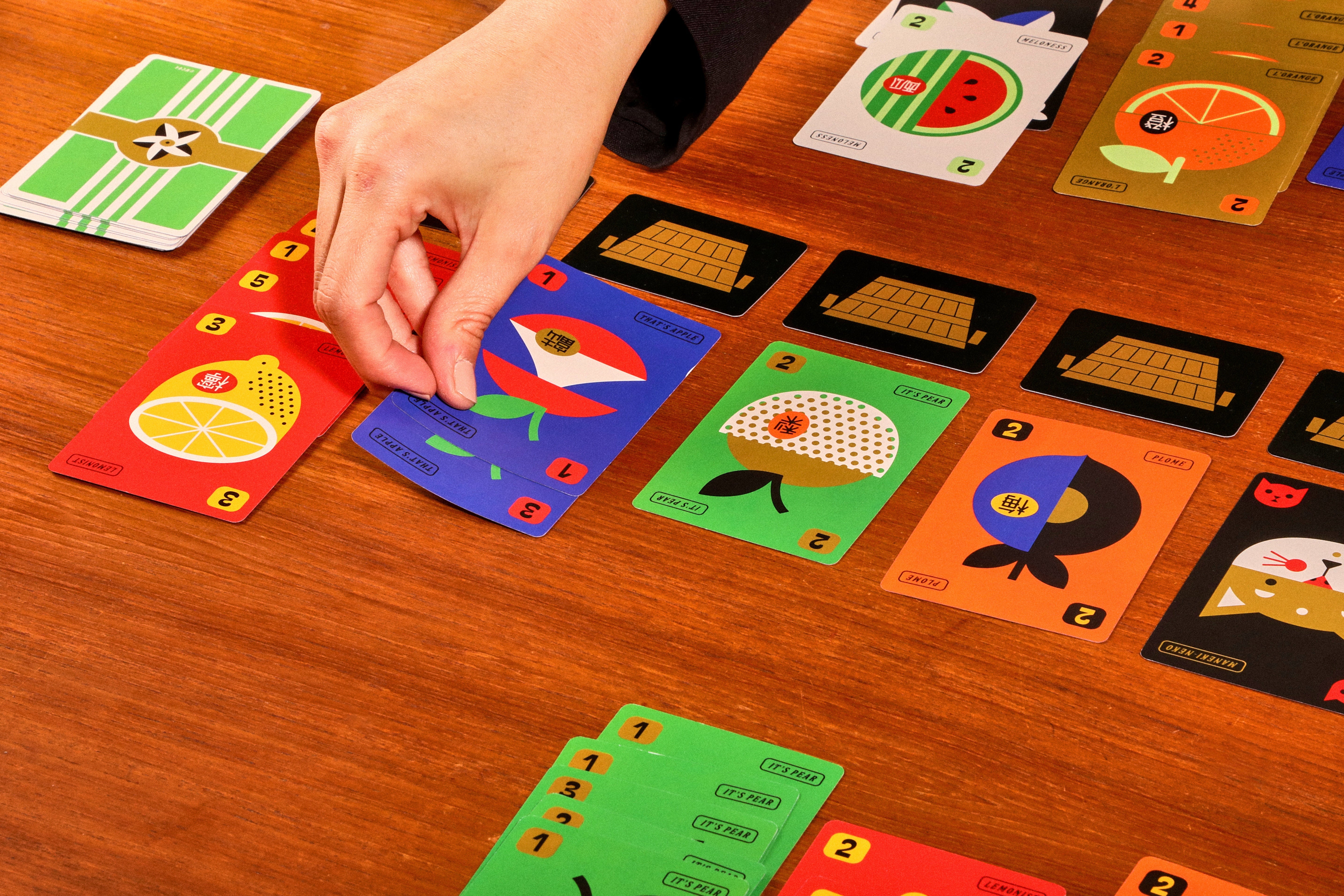 Hand playing a card game with colorful cards on a wooden table
