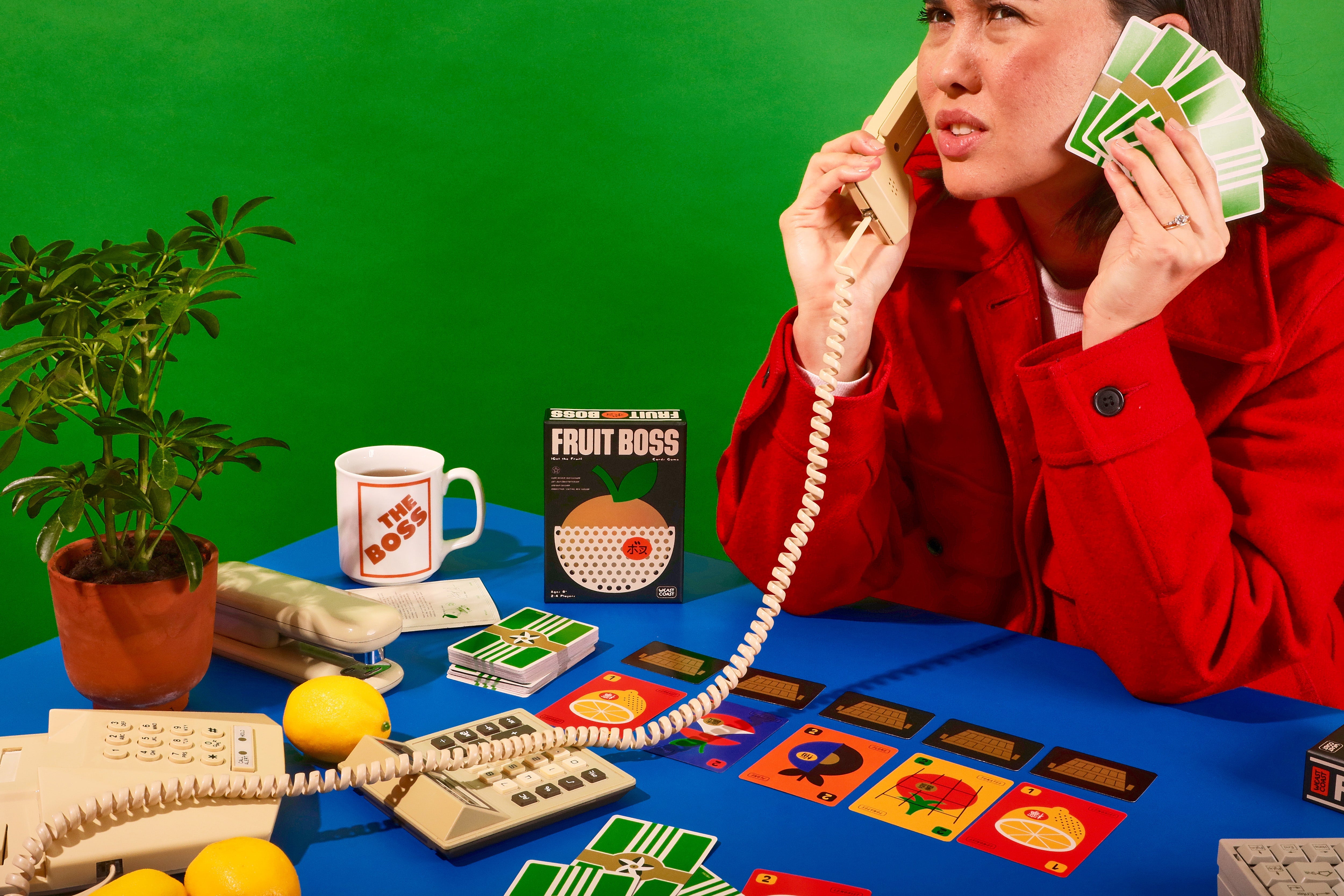 Person playing a card game with a green background, holding cards and using a phone.