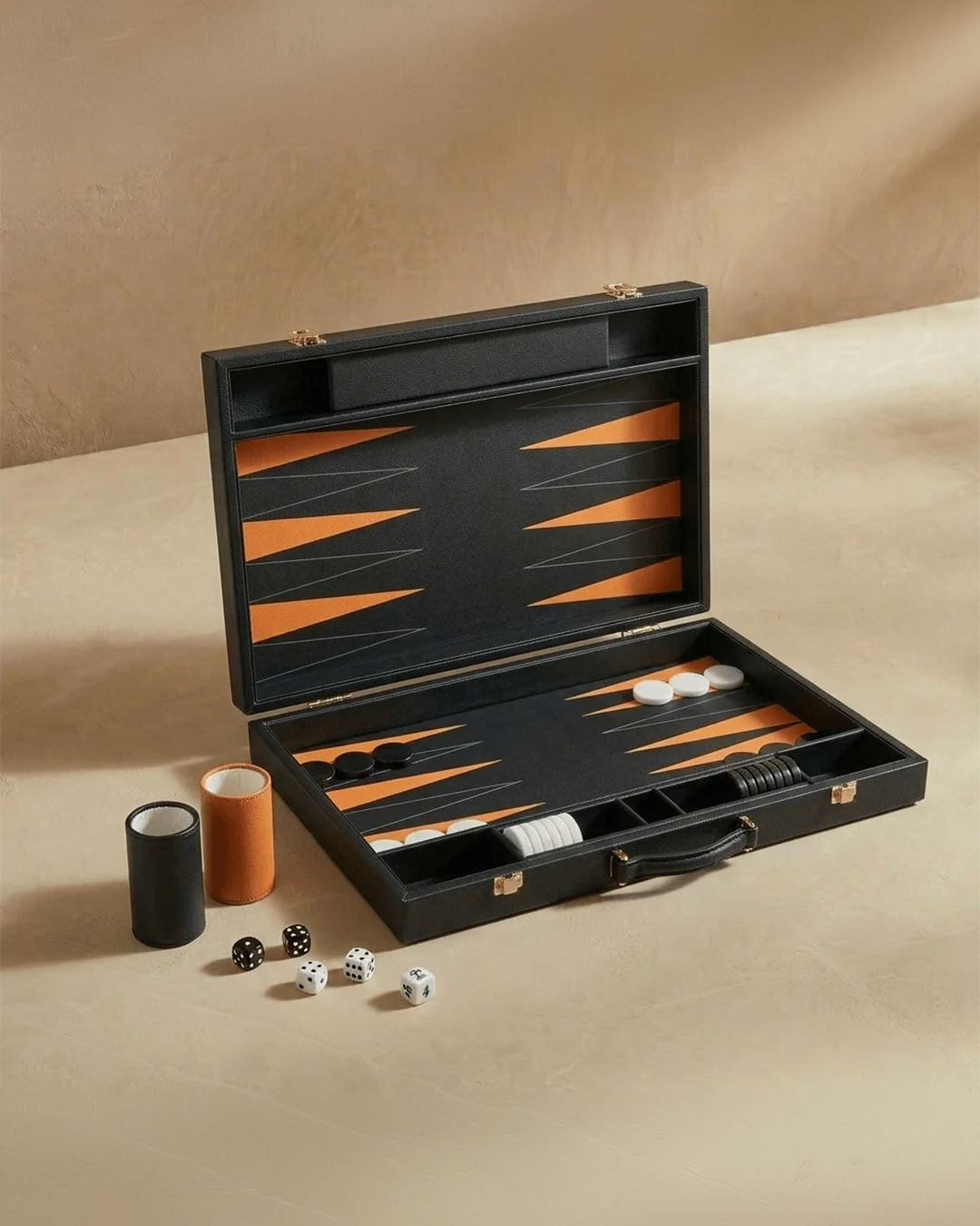 Black backgammon set with dice and pieces on a beige surface