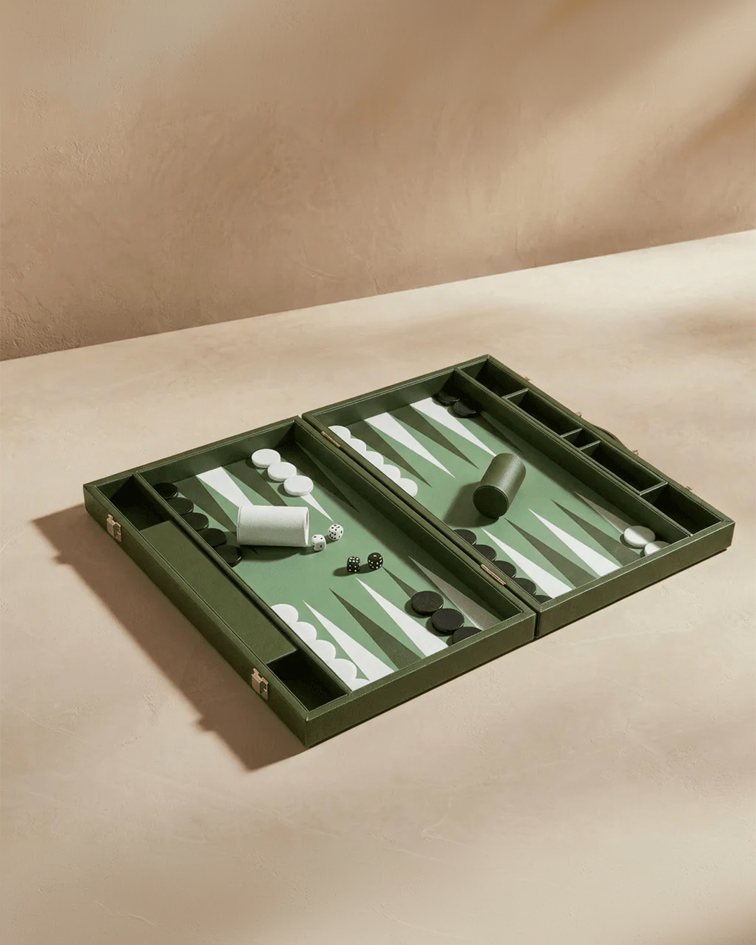 Green backgammon set on a beige surface