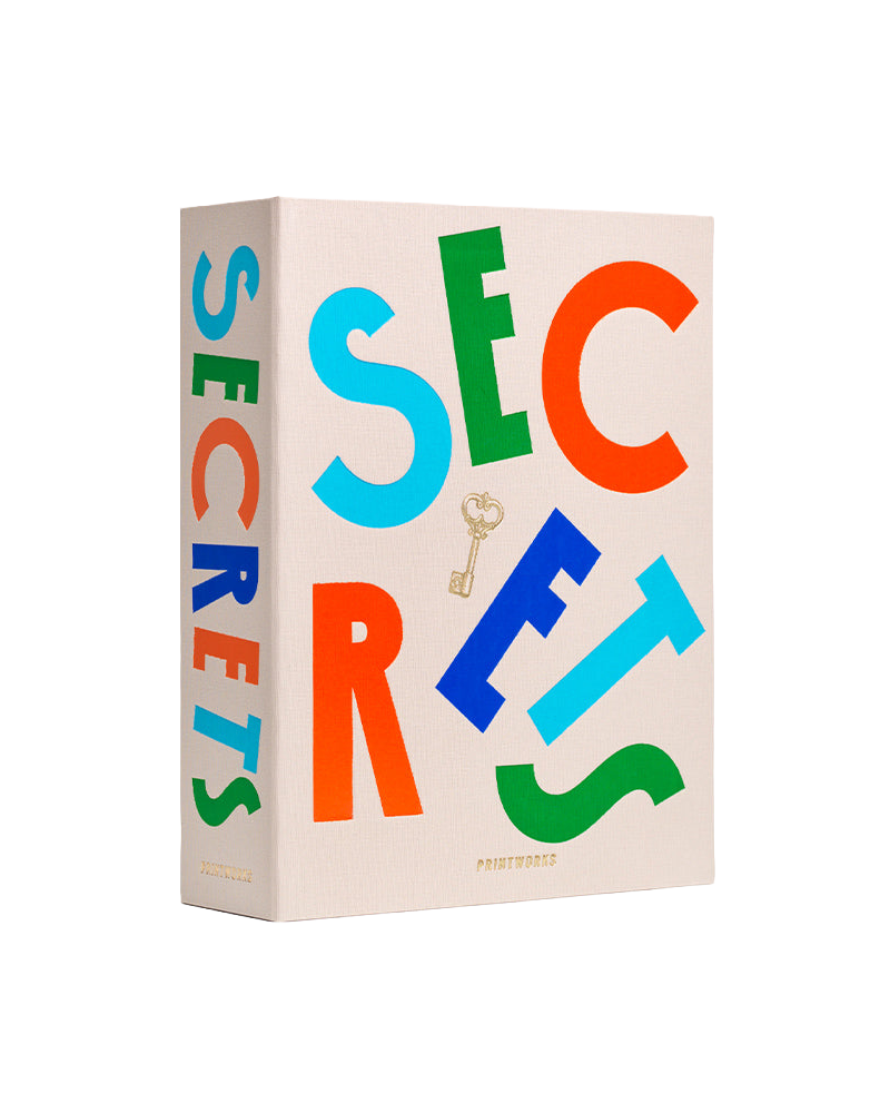 A hardcover book titled 'SECRETS' with large, colorful letters in blue, green, orange, and red on a cream-colored cover, featuring a small gold key graphic and the brand name 'PROTESTED' at the bottom.