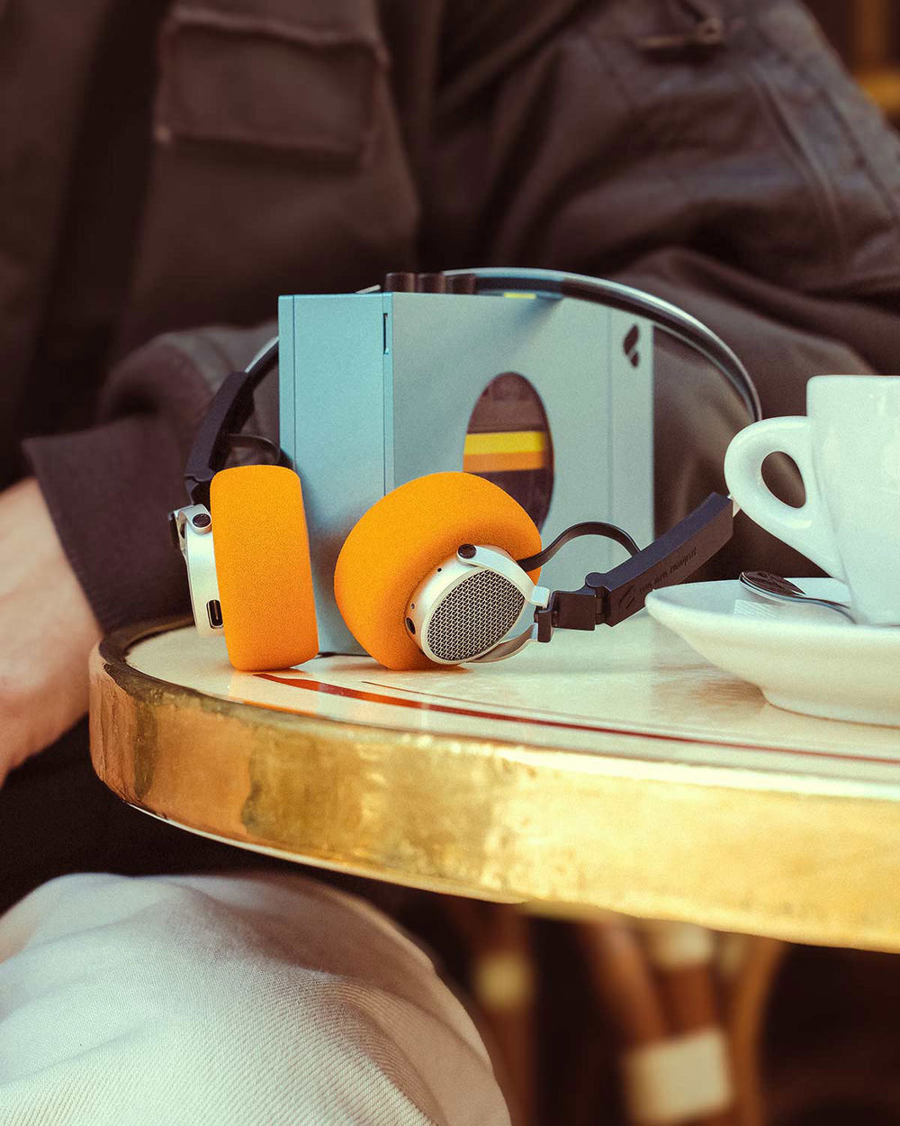 A retro cassette play with headphones resting on a cafe table next to a coffee cup