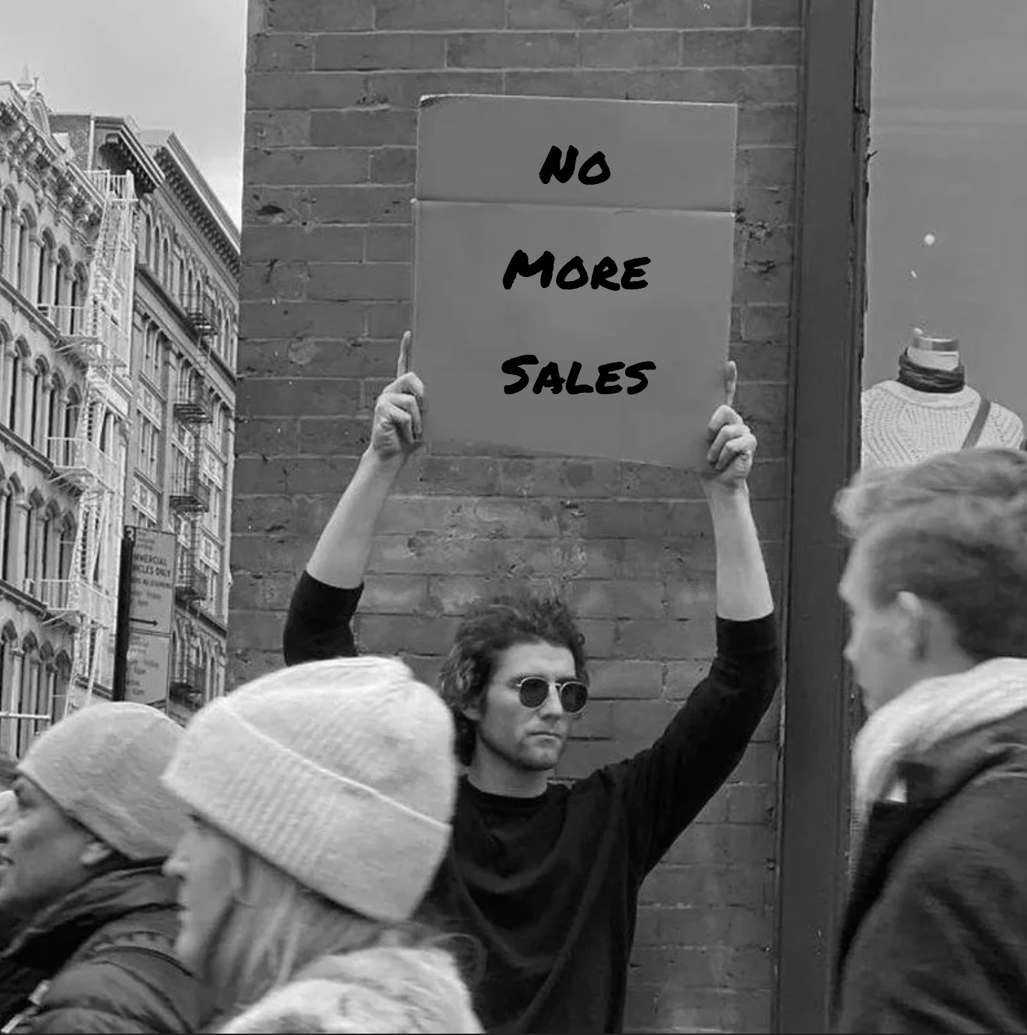 A man holds a sign that reads, "No More Sales" in the middle of a protest in New York City.