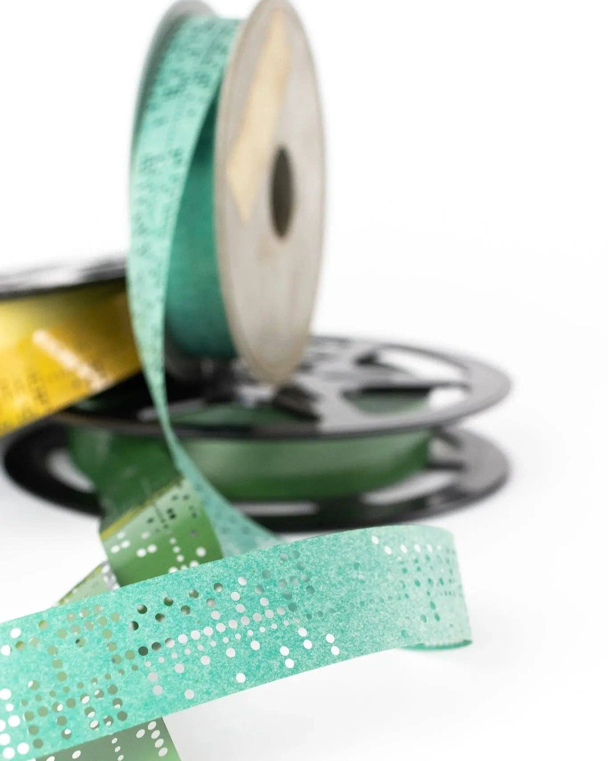 Green glittery ribbon on a spool with a white background