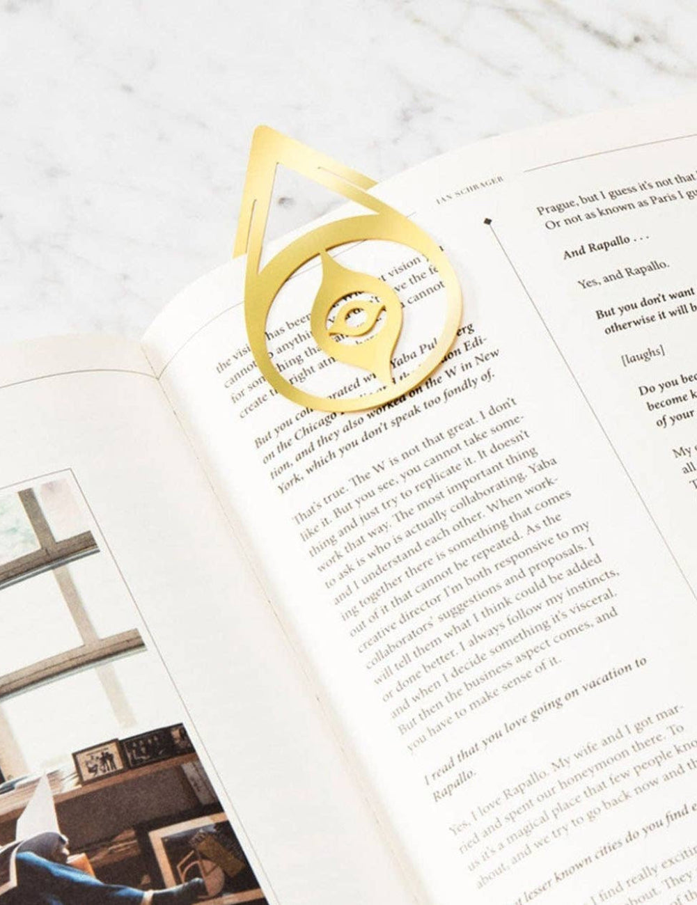 Open book with a gold bookmark on a light wooden surface