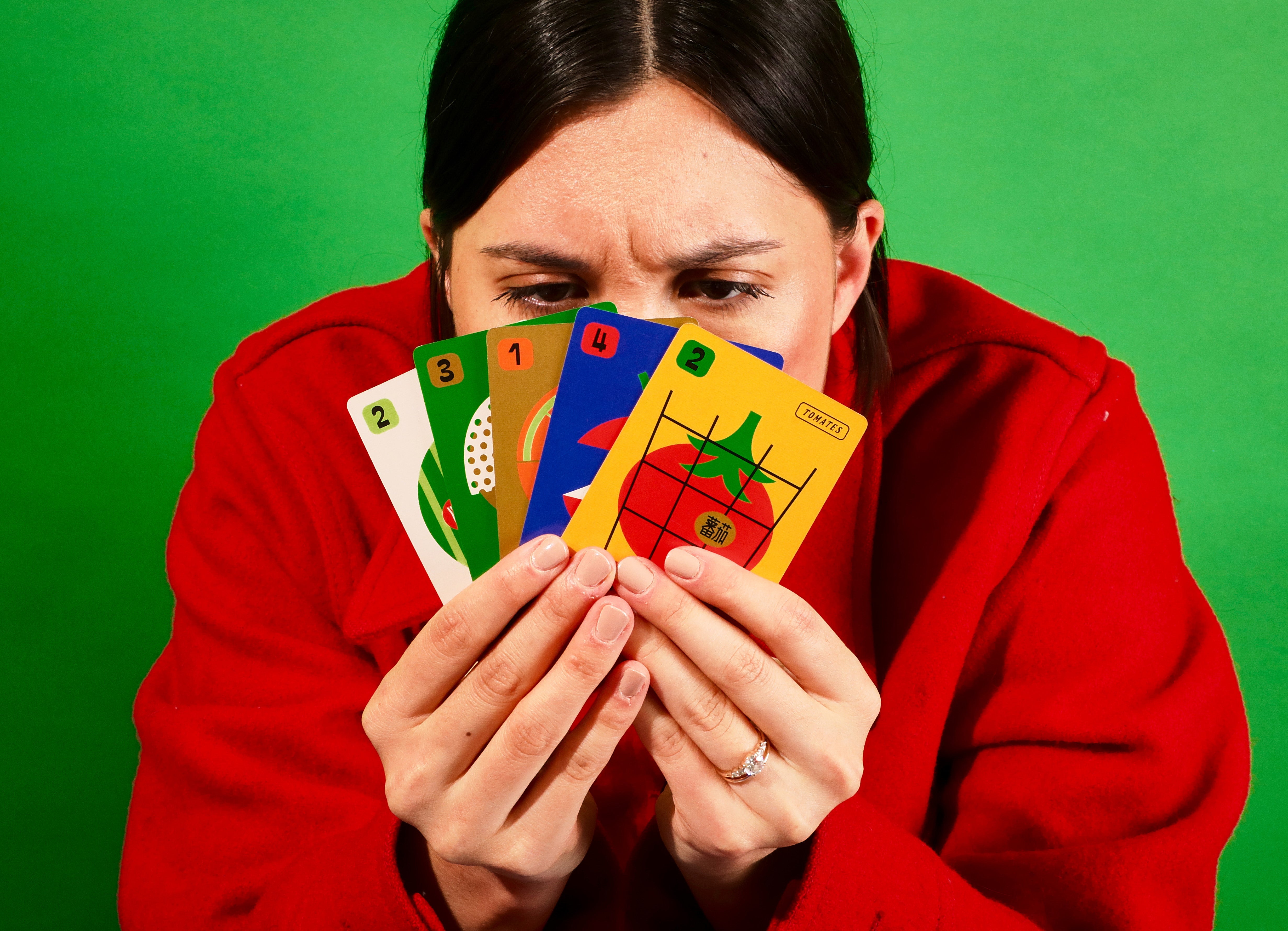 Person holding playing cards with a green background