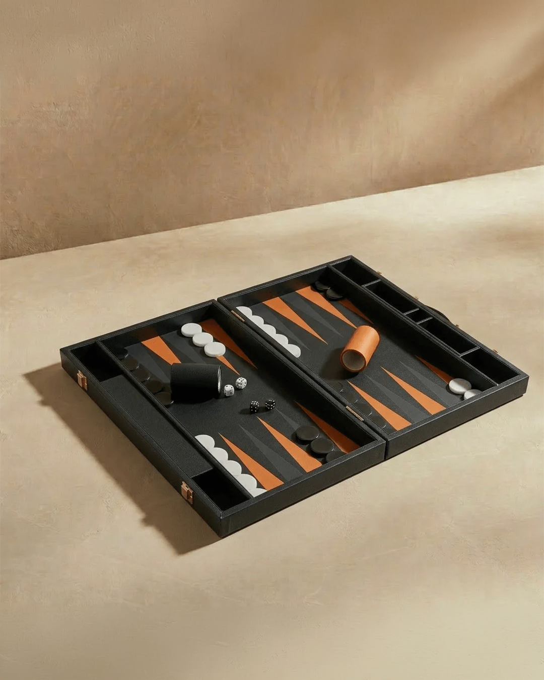 Backgammon set in a black case on a beige surface