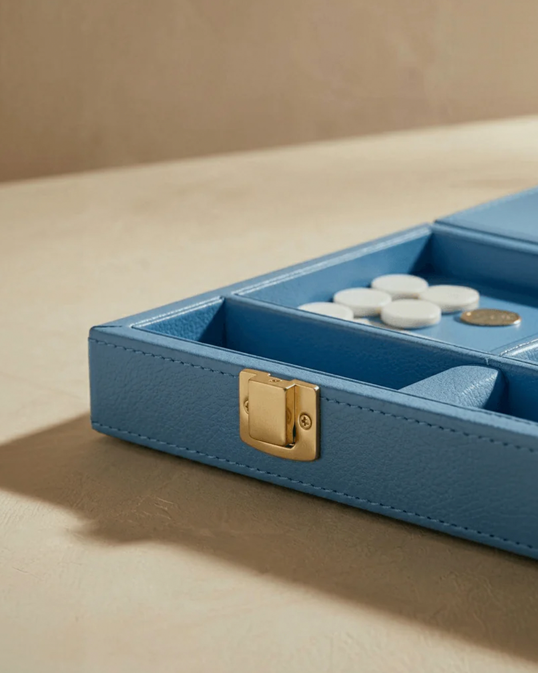 Blue jewelry box with gold clasp on a beige surface