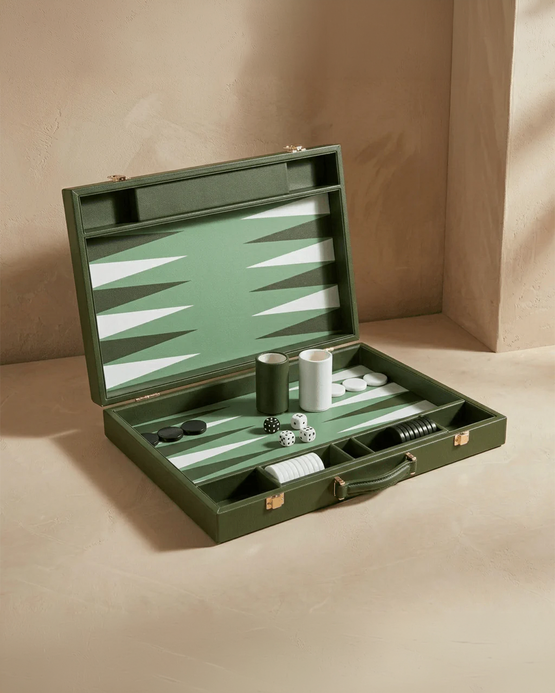 Green backgammon set with pieces and dice on a beige surface