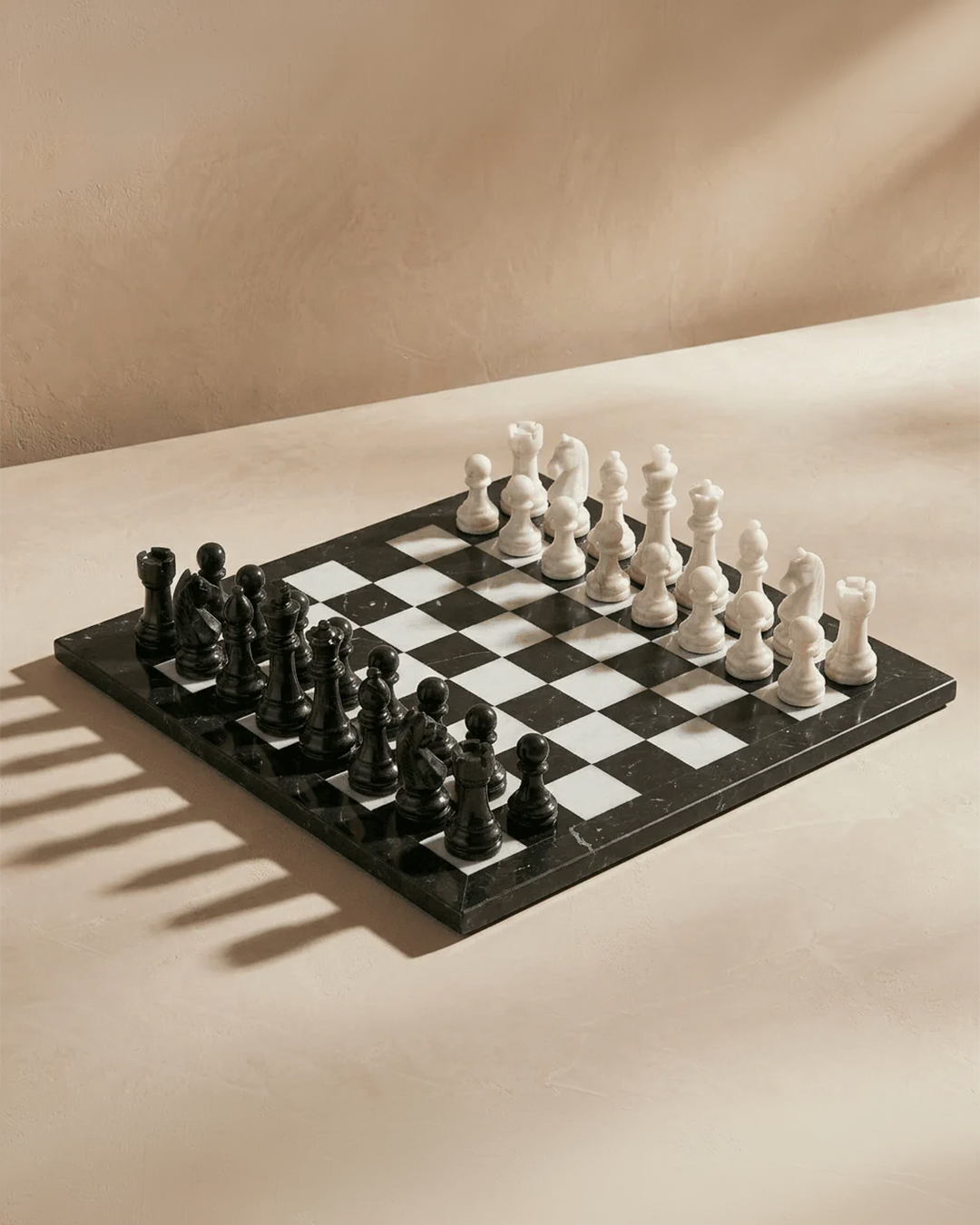 Chessboard with black and white pieces on a beige surface