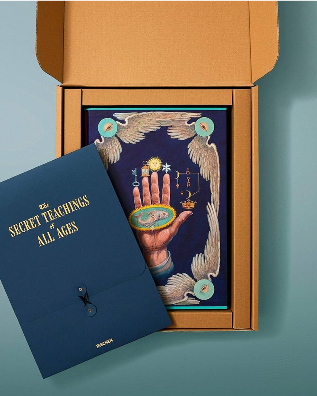Blue book titled 'The Secret Teachings of All Ages' with a tarot card design on a teal background