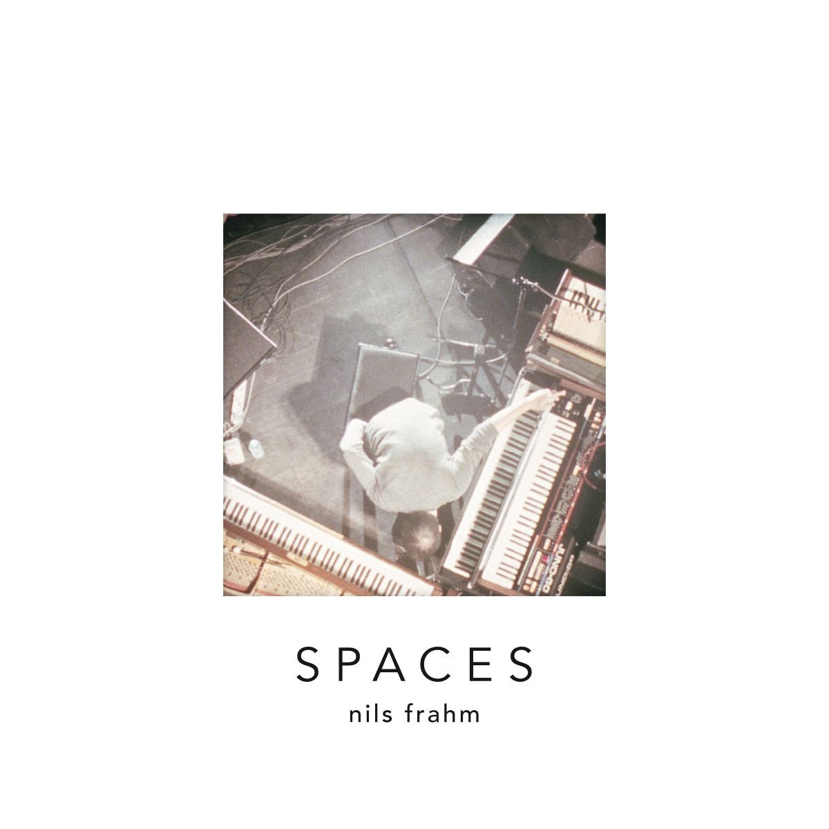 Album art for Spaces by Nils Frahm featuring a photo of a personal playing the keyboards from above.