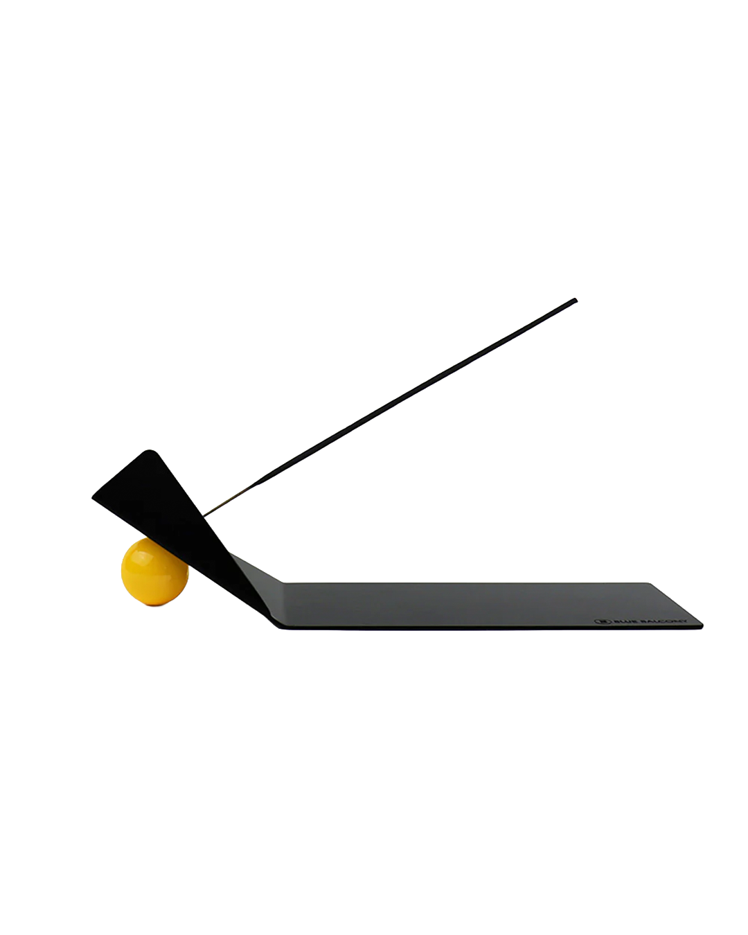 A minimalist black metal sheet with a bent corner propped up by a small yellow ball. A stick of incense protrudes from the ball. Shown on a plain white background.