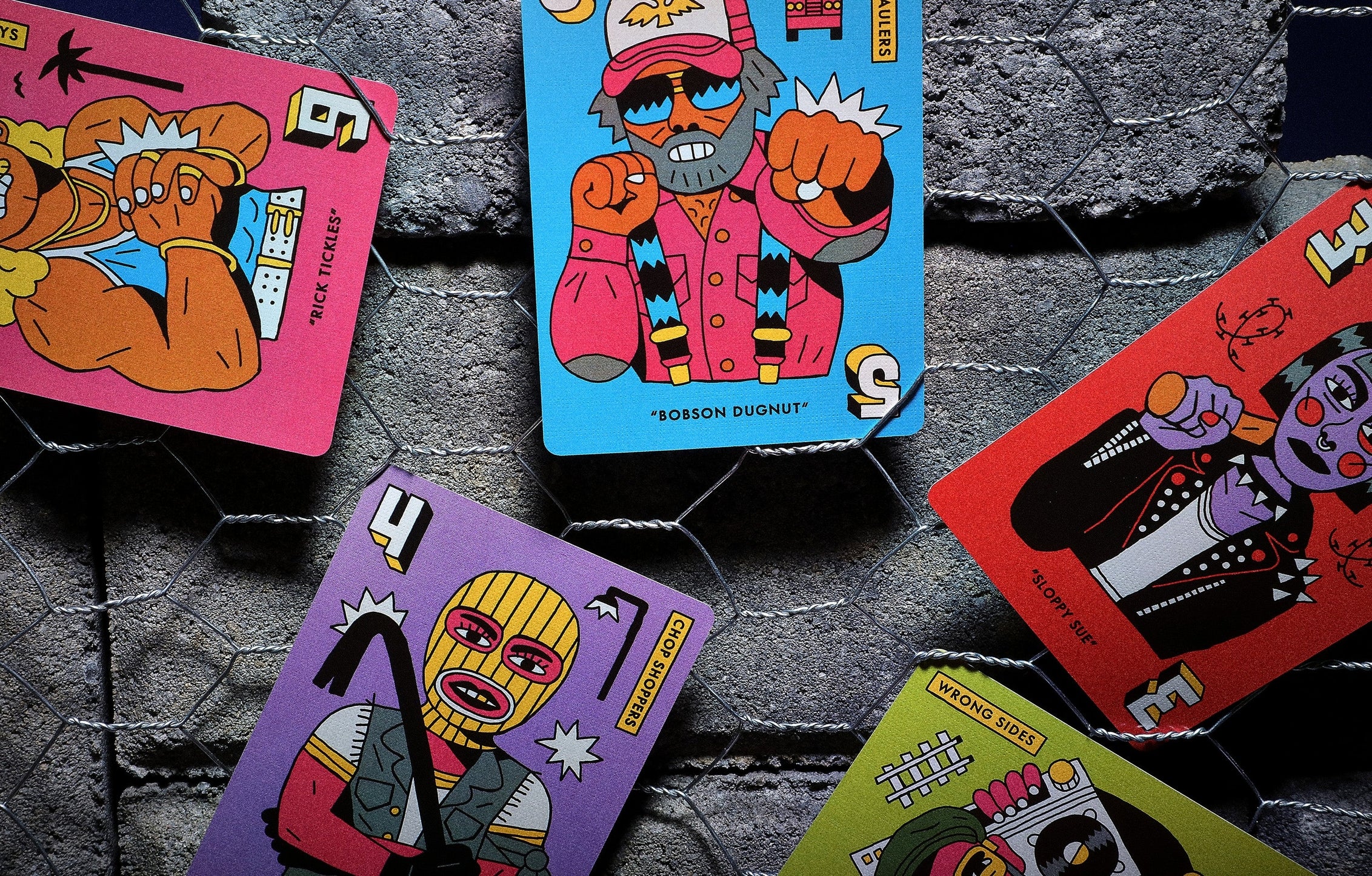 Colorful card designs with cartoon characters on a textured dark surface
