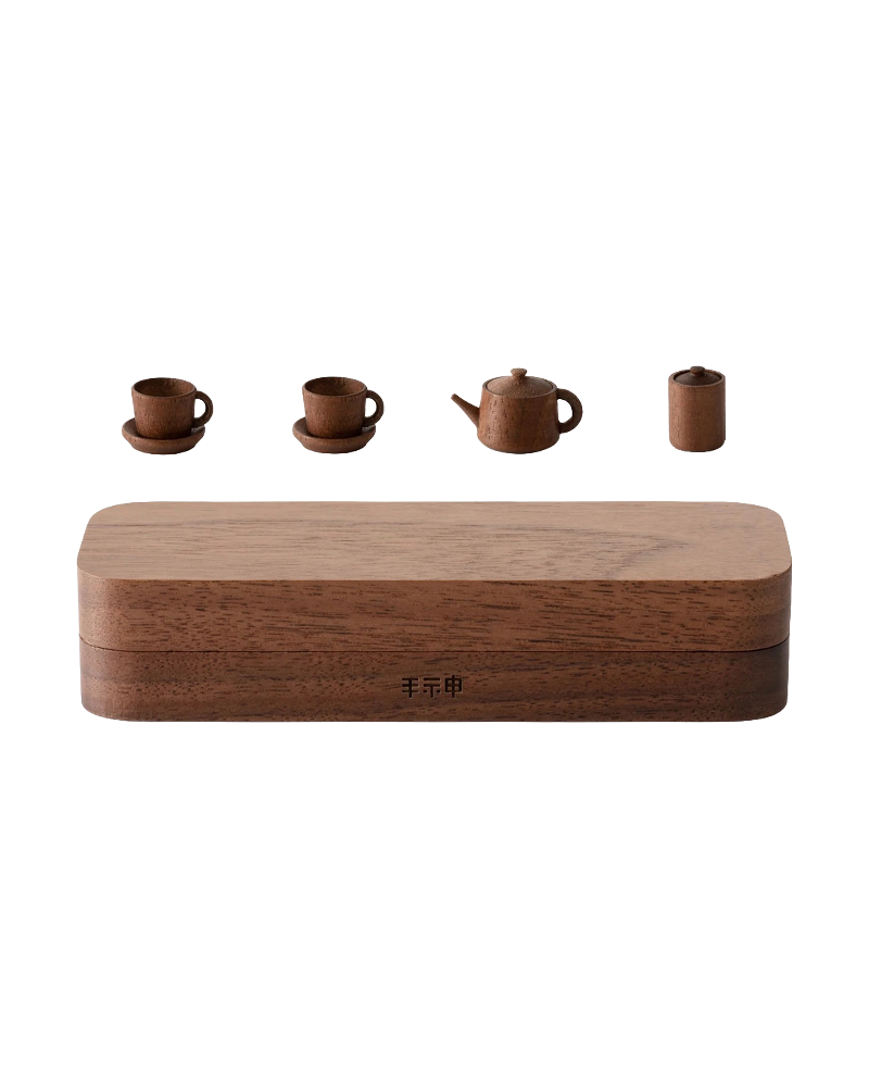 A wooden box with Japanese characters etched into it and a miniature tea set including two tea cups with saucers, a tea pot, and a jar with a lid.