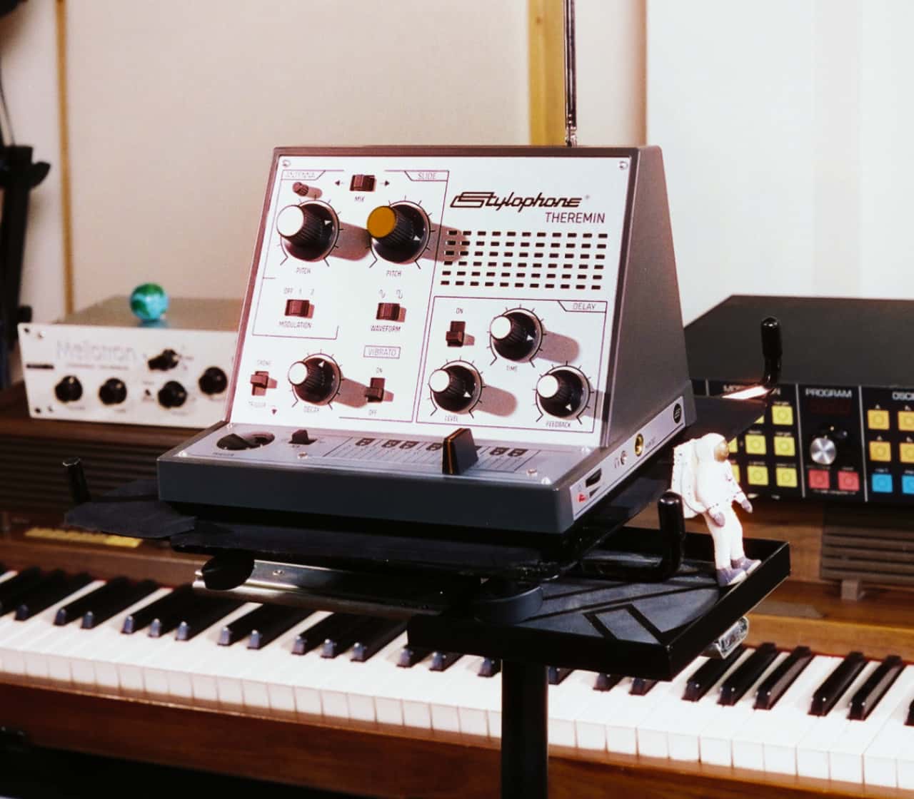 Vintage-style theremin controller on a stand with a keyboard in the background