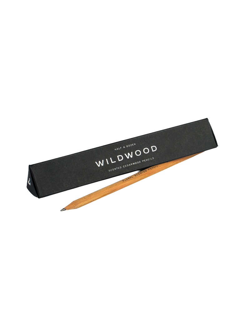 A single Wildwood half-wood graphite pencil resting diagonally on its black packaging box against a solid white background.